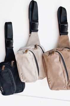 three small purses hanging on the wall with one black and one white bag attached to it