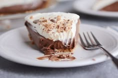 a slice of chocolate pie on a white plate with a fork next to the rest of the pie