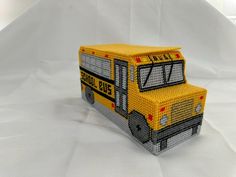 a yellow school bus made out of legos sitting on top of a white sheet