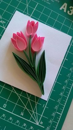 three pink tulips are sitting on top of a piece of paper