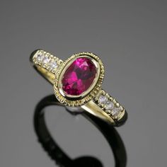 Elegance, sophistication, and sparkle make this ring a true treasure! Crafted by hand from 18K Treasure Gold made with 400 year-old shipwreck treasure and set with a 0.92ct pink tourmaline (rubellite), it contains a glittering row of diamonds for added sparkle. The shimmering water-ripple pattern on the band and beautiful Etruscan granulation is the perfect frame for this exquisite jewel. Dare to make a statement with a ring of timeless beauty! 18K Treasure Gold ring with a water ripple pattern Heirloom Ruby Ring With Gemstone Accents, Yellow Gold Ruby Ring With Tourmaline Center Stone, Classic Pink Ruby Ring With Bezel Setting, Heirloom Pink Ruby Ring, Shimmering Water, Treasure Gold, Ripple Pattern, Water Ripples, Shipwreck