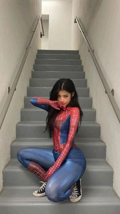 a woman dressed as spider - man is sitting on the stairs