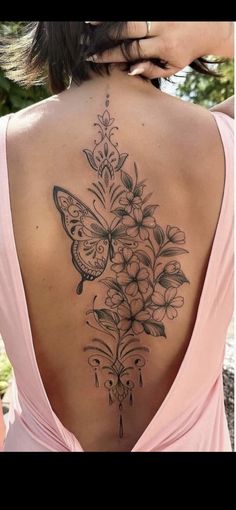 a woman's back tattoo with flowers and butterflies on it