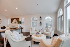 a living room filled with white furniture and lots of windows next to a counter top