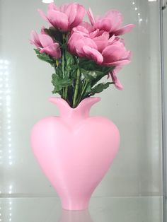 a pink vase filled with lots of flowers on top of a glass table next to a wall