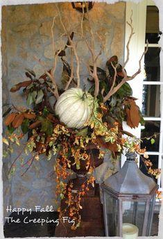 a white pumpkin sitting on top of a table next to a lantern and some leaves