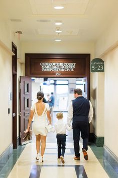 a man and woman walking down a hallway with a small child in front of them