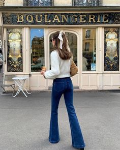 a woman is walking down the street in front of a store with her back to the camera