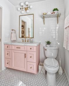 a white and pink bathroom with hexagonal floor tiles on the walls, toilet, sink, and mirror