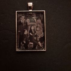 an old photo is hanging on a black surface with a silver frame that has the image of people in it