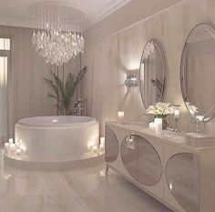 an elegant bathroom with candles, chandelier and bathtub in white marble finish