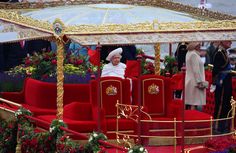 the queen is riding in a carriage with red seats and gold trimmings on it