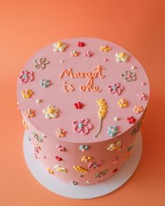 there is a pink cake with flowers on the top that says marott is o'clock