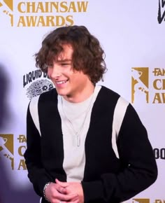 the young man is smiling for the camera on the red carpet at the awards ceremony