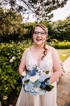 a woman wearing glasses and holding a bouquet in front of her is smiling at the camera