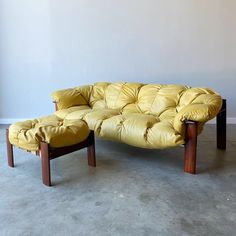 a yellow leather couch sitting on top of a cement floor next to a wooden frame