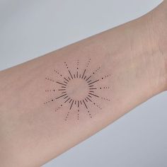 a person's arm with a small sun tattoo on it