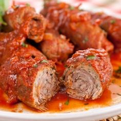 meatballs covered in marinara sauce on a white plate sitting on a wicker place mat