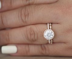 a woman's hand with a diamond ring on top of her finger and the other hand holding an engagement ring