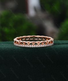 a diamond ring on top of a green velvet surface with trees in the back ground