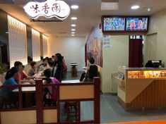 people sitting at tables in a restaurant with menus on the wall and television screens above them