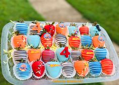 a tray filled with lots of different colored cupcakes on top of a table