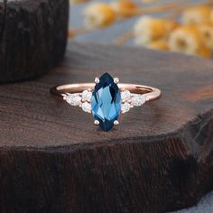 a blue and white diamond ring sitting on top of a wooden table next to a piece of wood