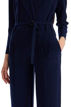 Made of comfortable poly lycra with laser-cut trims, this Norma Kamali jumpsuit boasts a surplice top that replicates a double-breasted jacket with peaked lapels, padded shoulders and an internal hook-and-loop closure. The waist is defined by front pleats and a matching D-ring belt, then falls into a pair of fluid, straight pants with side pockets. The model is 177 cm tall and wears a size XS. Composition: 95%PL, 5%EA Sleek V-neck Jumpsuits And Rompers For Work, Elegant Jumpsuits With Belted Cuffs, Sleek Fall Workwear Jumpsuits And Rompers, Sleek Workwear Jumpsuits And Rompers For Fall, Sleek Jumpsuits And Rompers For Fall Workwear, Formal Solid Belted Jumpsuit, Chic V-neck Business Casual Pantsuit, Elegant Fitted Jumpsuits And Rompers For Business Casual, Elegant Belted Jumpsuits And Rompers For Office