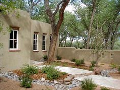 an adobe style house surrounded by trees and rocks