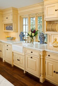 an elegant kitchen with blue and white vases on the countertop, yellow cabinets