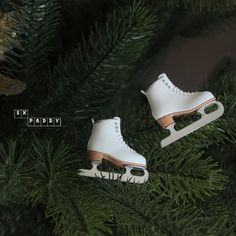 two white ice skates sitting on top of a christmas tree