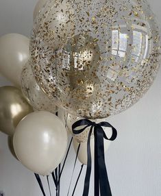 some balloons that are in the air with gold and white confetti on them