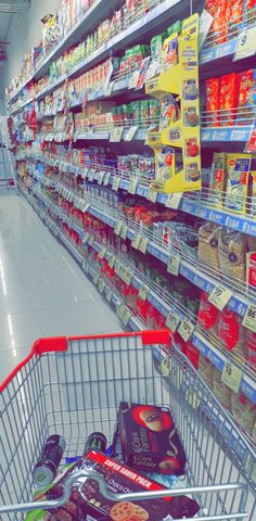 a shopping cart in a grocery store filled with snacks and drinks on the shelves next to each other