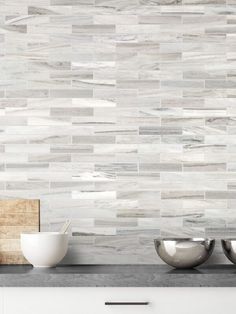 two bowls are sitting on the counter in front of a wall with white tile and wood