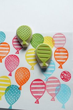 two rubber stamps sitting on top of a piece of paper with balloons in the background