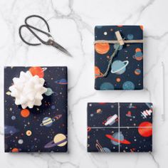 wrapping paper and scissors on a marble surface with space themed wrapping material, including an origami flower