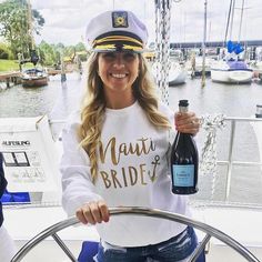 a woman in a sailor's hat holding a bottle of wine on a boat