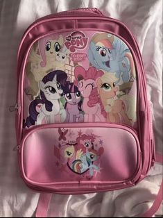 a pink backpack with many little ponys on the front and back sides, sitting on a bed