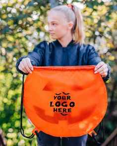 a woman holding an orange bag with the words logo here on it in front of her