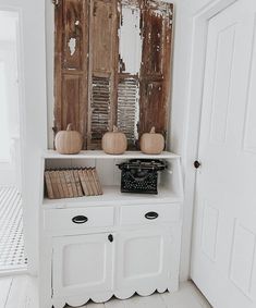 At the entryway to the bathroom sits a white shelf with antique farmhouse decor including books, a typewriter on display, and old shutters that hang above. The shutters were once white, but time has worn them down to their original wood stain, perfect for a farmhouse-themed corner...   Image: waynesvillewhitehouse