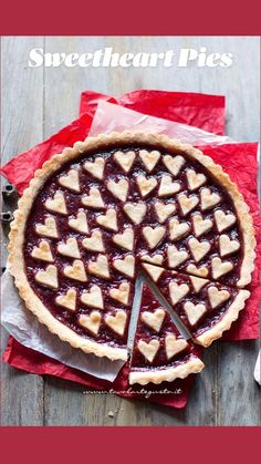 a pie with hearts cut out of it sitting on top of a red napkin next to a knife and fork