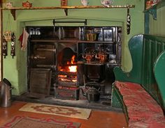 an old fashioned stove with pots and pans on it's burners in a green room