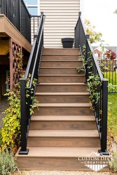 a set of stairs with black railings and wooden steps leading up to a house