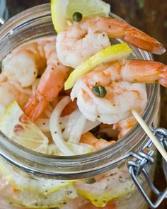 a glass jar filled with shrimp and lemon wedges