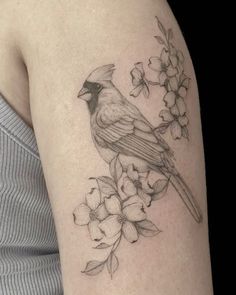 a bird sitting on top of a branch with flowers in it's back arm