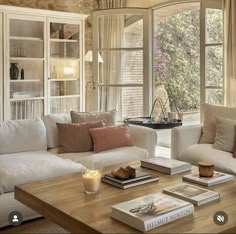 a living room filled with white furniture and lots of books on top of a wooden table