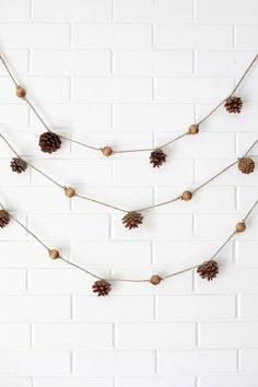 pinecone garland on white brick wall with string and wood beads hanging from it