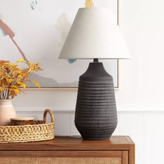 two vases sitting on top of a wooden table next to a basket and lamp