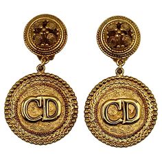 CHRISTIAN DIOR Boutique vintage gold tone logo CD dangling earrings (clip-on). Embossed CHRISTIAN DIOR Boutique. Indicative measurements : height approx. 6 cm (2.36 inches) / max. width approx. 3.5 cm (1.38 inches). Material : Gold tone metal hardware. Weight per earring : approx. 20 grams. NOTES - This is a preloved vintage item, therefore it might have imperfections. - Colors may differ slightly from actual product appearance due to differences in lighting conditions. - As a buyer, you are fully responsible for customs duties, other local taxes and any administrative procedures related to imports into the country of destination. Classic Gold Clip-on Earrings With Logo Plaque, Designer Gold Metal Clip-on Earrings, Luxury Gold Clip-on Earrings With Logo, Elegant Gold Earrings With Logo Charm, Gold Designer Metal Clip-on Earrings, Designer Gold Drop Clip-on Earrings, Luxury Gold Earrings With Logo Charm, Fashion Trend Board, Dior Boutique