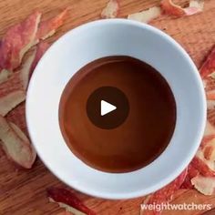 a cup of coffee sitting on top of a wooden table next to sliced bacon pieces